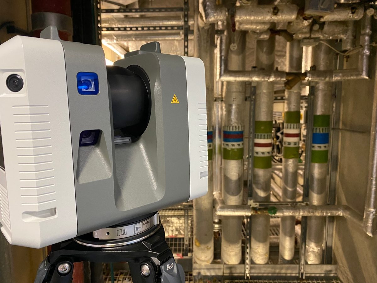 Leica RTC360 laser scanner on a tripod in a plant room, in front of insulated pipework risers